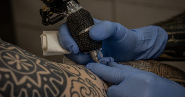 Professional tattoo consultation showing clean workspace with artist and client discussing design options and shop selection