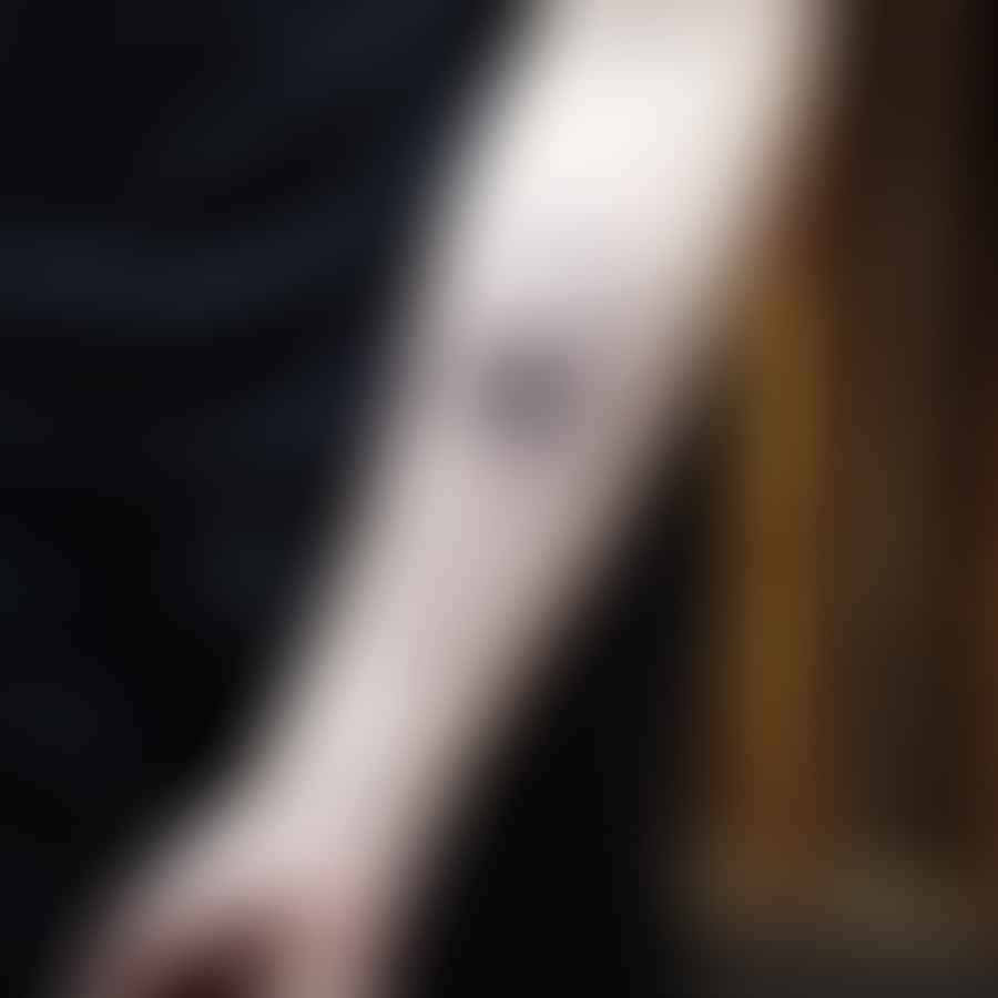 A beautiful geometric white ink tattoo on a forearm